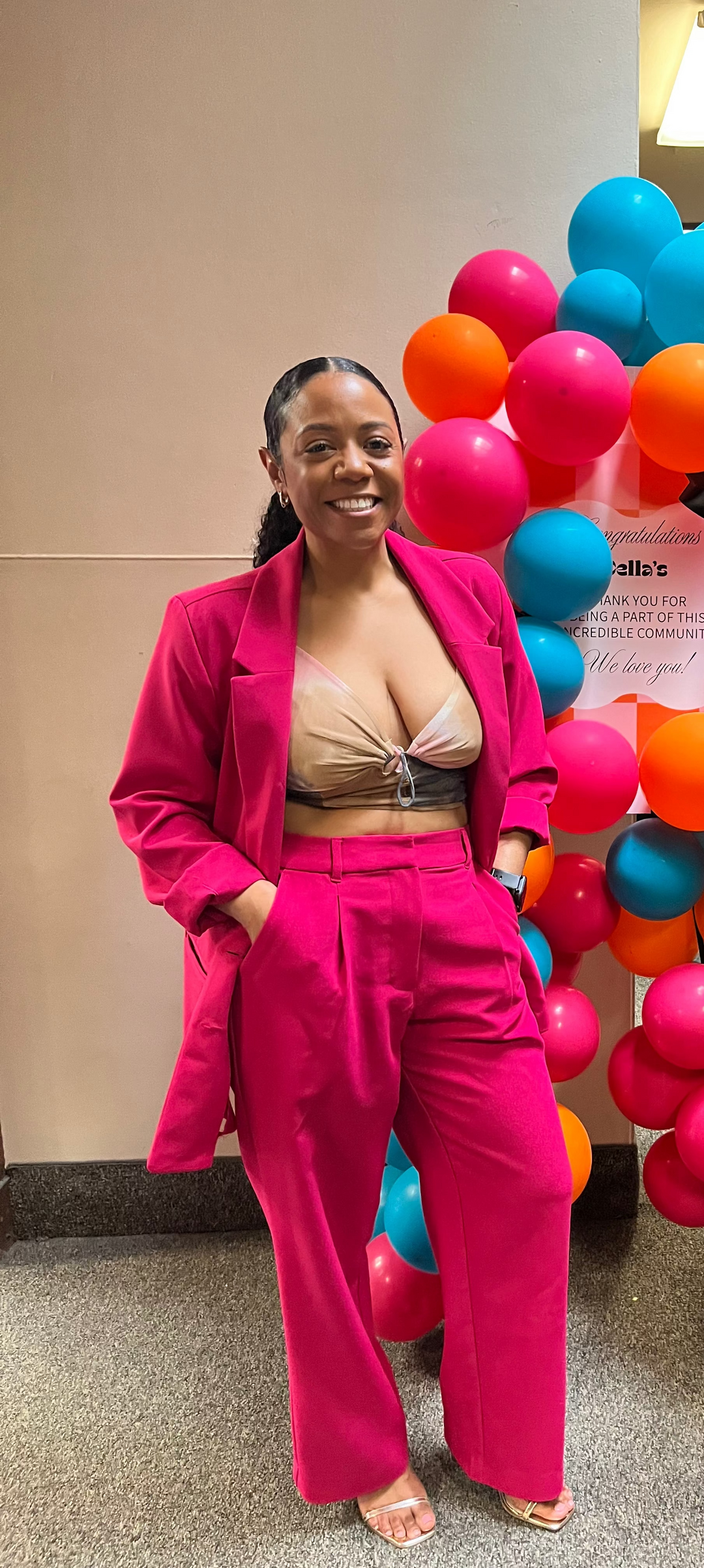 Woman standing in front of a colorful balloon display in an indoor setting.